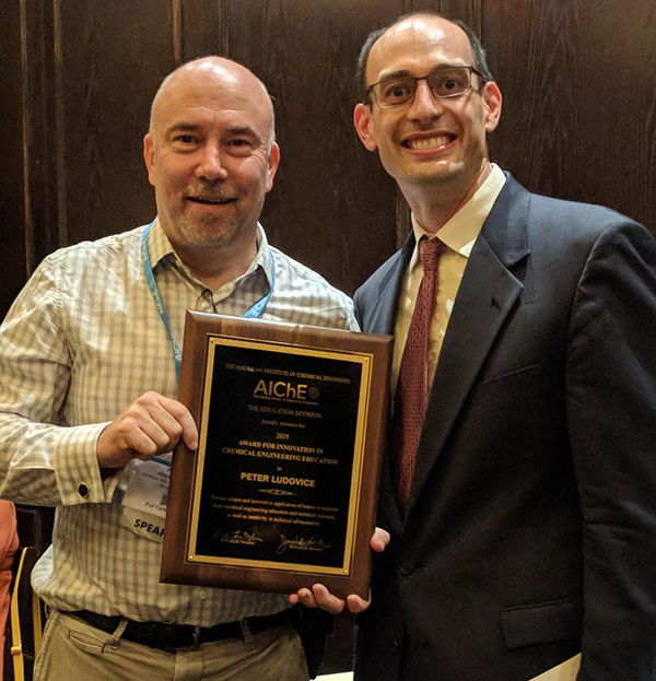 Two men holding a plaque in front of them.